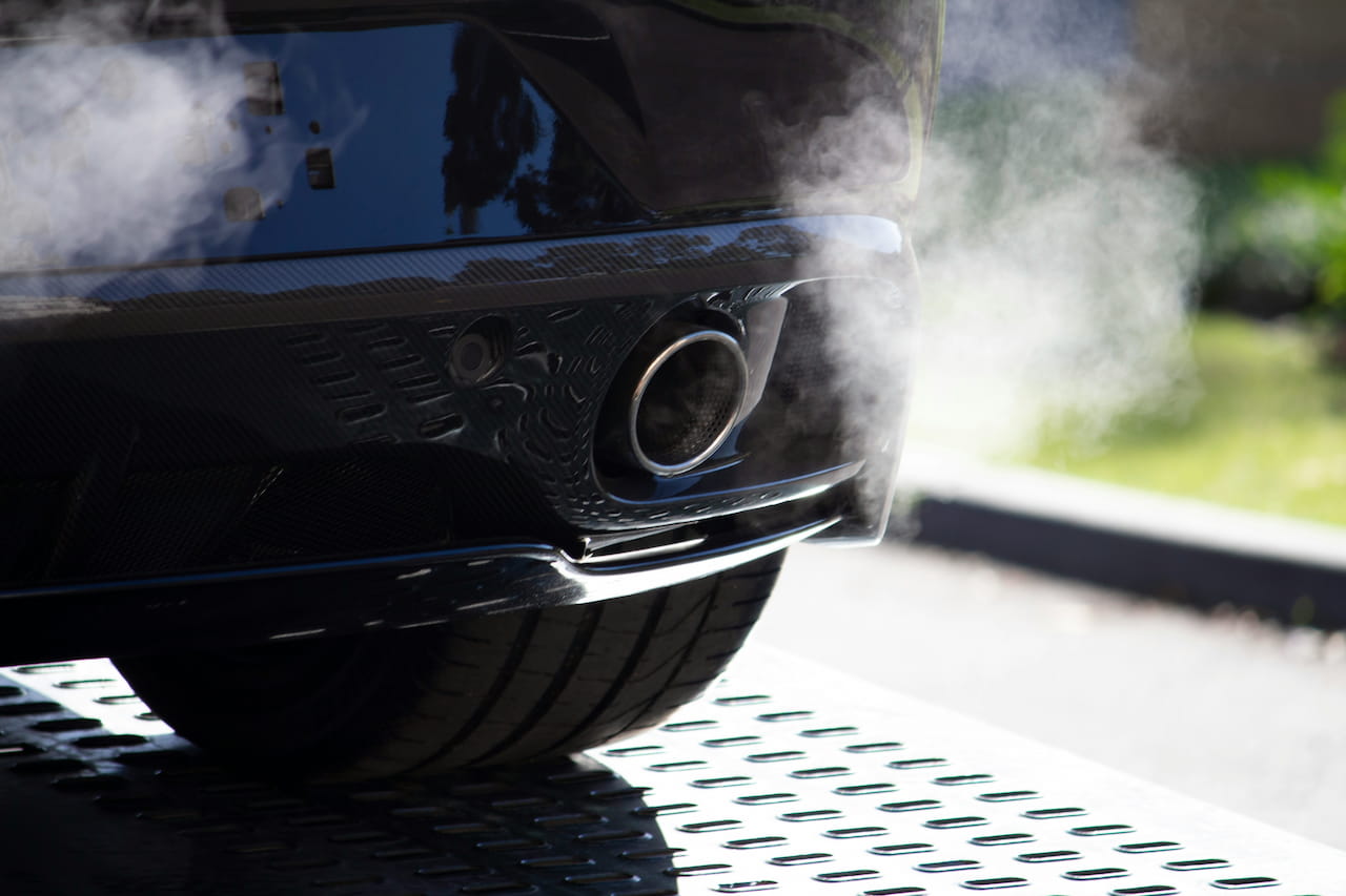 Close-up of a car tailpipe with exhaust fumes